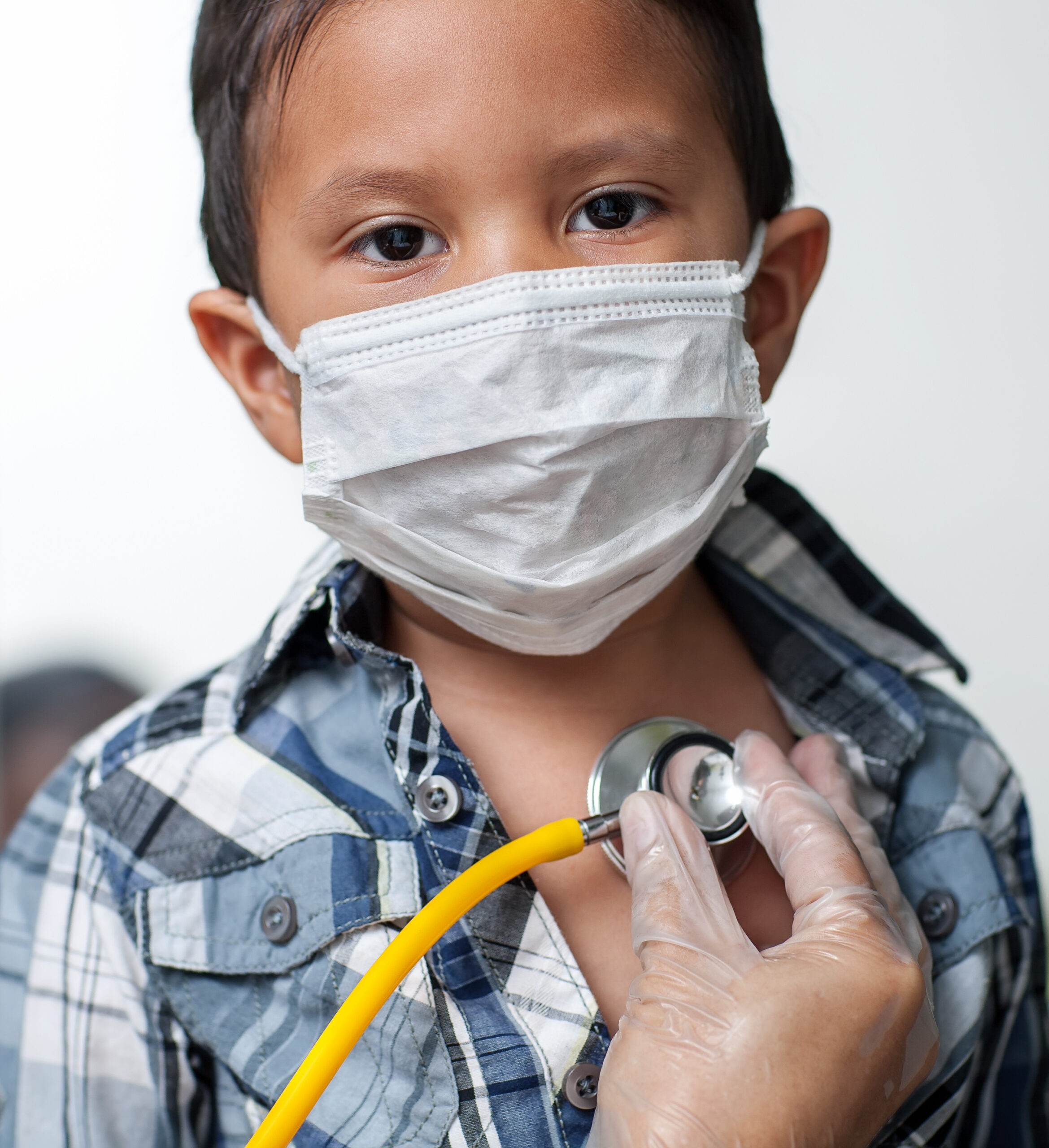 young latino boy wearing a mask getting his heart checked